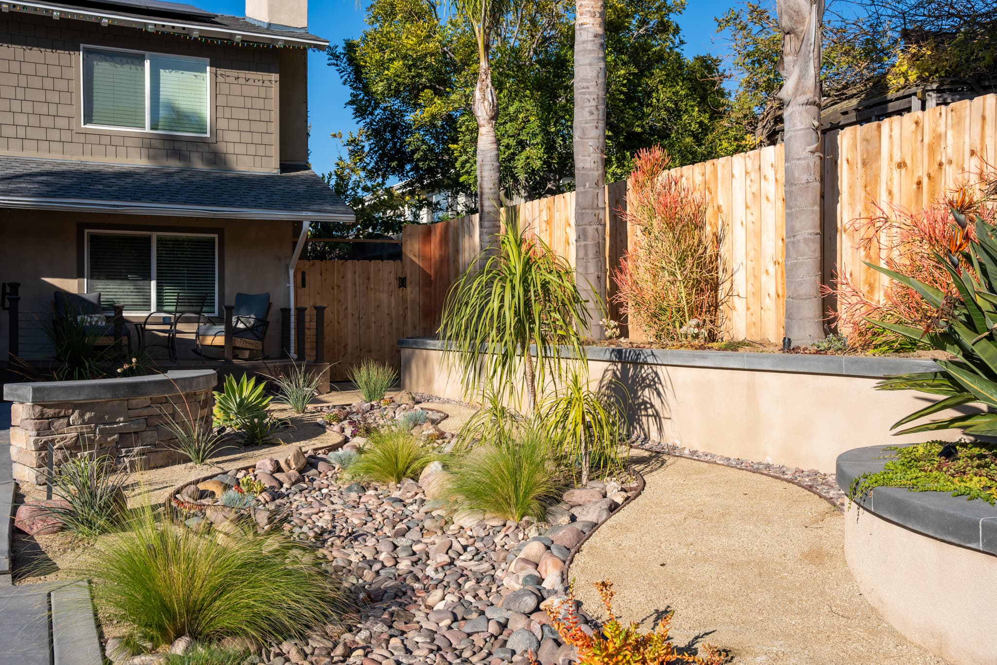 Front yard with xeriscape design featuring agave, palms, and river rocks
