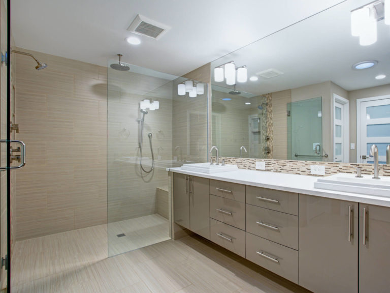 Bathroom tan vanity cabinets & tan flooring with frameless shower