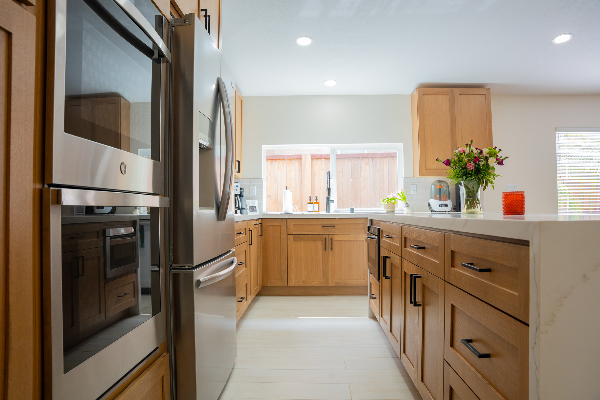 Kitchen renovation with large windows, farmhouse sink, and marble-inspired countertops.
